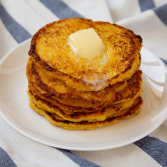 Homemade corn meal Johnny cakes with butter on a white plate, side view. Closeup.