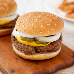 Homemade Mississippi Slug Burger with onion rings on a rustic wooden board, side view. Closeup.