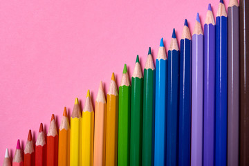 Color pencils on pink pastel background, close up. Set of colorful pencils, copy space. Crayons. Top view, flat lay. Back to school, college concept. Abstract background