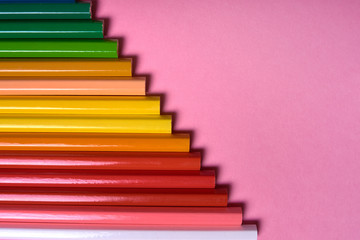 Color pencils on pink pastel background, close up. Set of colorful pencils, copy space. Crayons. Top view, flat lay. Back to school, college concept. Abstract background