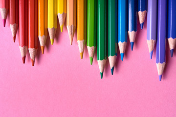 Color pencils on pink pastel background, close up. Set of colorful pencils, copy space. Crayons. Top view, flat lay. Back to school, college concept. Abstract background