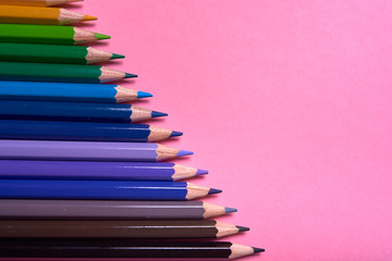 Color pencils on pink pastel background, close up. Set of colorful pencils, copy space. Crayons. Top view, flat lay. Back to school, college concept. Abstract background