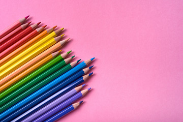 Color pencils on pink pastel background, close up. Set of colorful pencils, copy space. Crayons. Top view, flat lay. Back to school, college concept. Abstract background