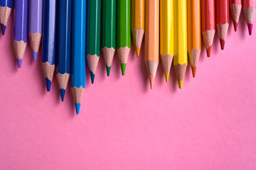 Color pencils on pink pastel background, close up. Set of colorful pencils, copy space. Crayons. Top view, flat lay. Back to school, college concept. Abstract background
