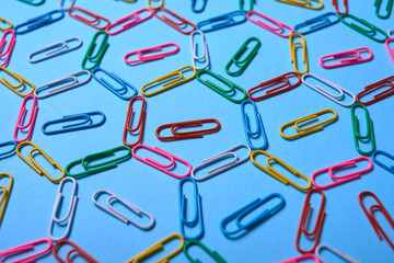 Colorful paper clips on blue pastel texture, copy space. Top view, flat lay. Back to school, business, education concept. Abstract background