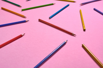 Color pencils on pink pastel background, close up. Set of colorful pencils, copy space. Crayons. Top view, flat lay. Back to school, college concept. Abstract background