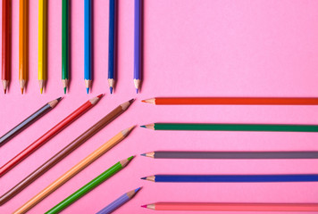 Color pencils on pink pastel background, close up. Set of colorful pencils, copy space. Crayons. Top view, flat lay. Back to school, college concept. Abstract background