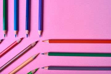 Color pencils on pink pastel background, close up. Set of colorful pencils, copy space. Crayons. Top view, flat lay. Back to school, college concept. Abstract background