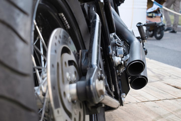 A view of a powerful motorcycle from a rear angle. Two exhaust pipes and a frayed wheel convey a sense of readiness at any time for a quick start.