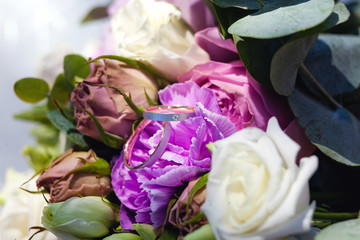 wedding rings on a bouquet of purple flowers