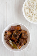 Homemade Filipino Adobo Pork with rice on a white wooden surface, top view. Flat lay, overhead, from above. Copy space.