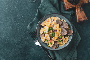 Pasta with black truflle and green peas in blue bowl.