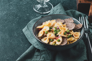 Pasta with black truflle and green peas in blue bowl.