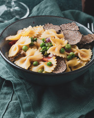 Pasta with black truflle and green peas in blue bowl.