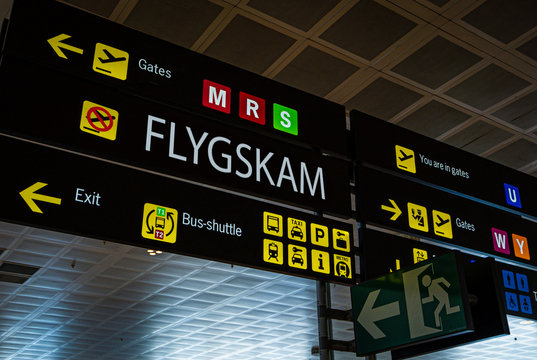 Information panel with Flygskam word on it at an international airport.. Flygskam or flight shame in Swedish refers to the feeling of being ashamed or embarrassed to board a plane because of its