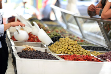 Sprzedawca oferuje oliwki na straganie, w markecie, na rynku miasta Wocław.