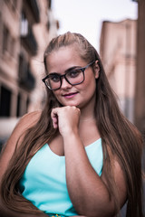Short portrait of blonde girl with glasses with fist on chin