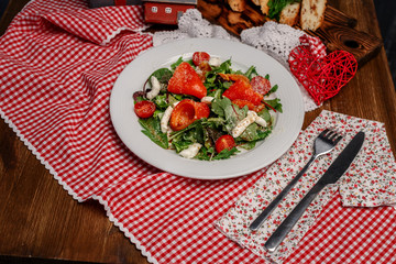 tomatoes, peppers and greens on a white plate and slices of bread with herbs on a wooden tray