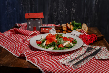 tomatoes, peppers and greens on a white plate and slices of bread with herbs on a wooden tray