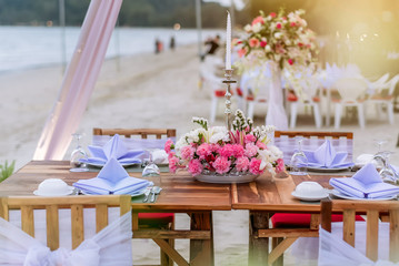 Romantic dinning table on the beach . Table setting at a luxury wedding and Beautiful flowers on the table. dinner table on the sand beach.