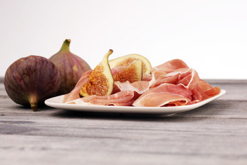 Italian prosciutto crudo or jamon with sliced figs Raw ham.