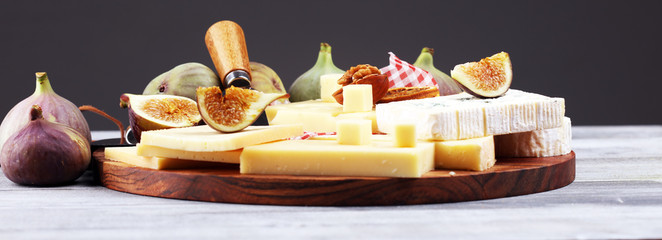 Cheese platter with different cheese and grapes and figs and nuts.