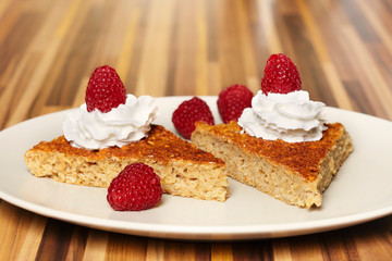 Tasty cake made of oat flakes covered with heavy cream and raspberries