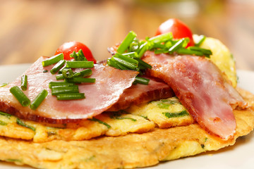 Healthy omelette made of eggs, oatmeal, beacon, chive and tomatoes