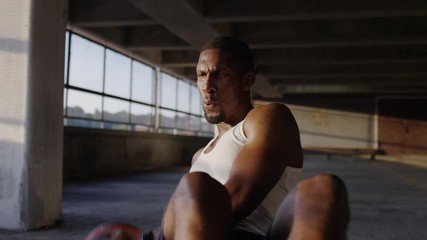 Straight on shot of athletic black male doing ab exercises with a heavy medicine ball, in slow motion