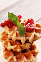 Traditional belgian waffles with fresh mint, sugar and raspberries on table