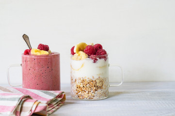 Banana, raspberry, oatmeal and yogurt smoothie and ingredients in two glass cups