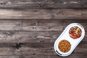 Dry pet food in bowl on brown wooden table