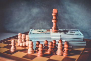 Boss and leader in business concept with king of chess on a dollars and  pawns below