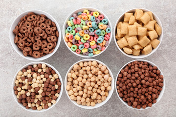 Various corn flakes in bowls on grey background