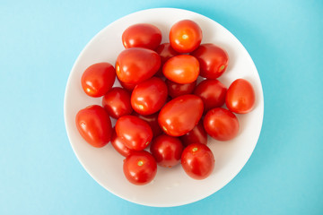 red tomatoes in white plate on blue background