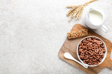 Chocolate corn rings with milk in jar and granola bar on grey background
