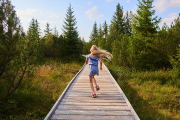 Child blond girl enjoying nature in Jezerni slat (Lake Moor) in National Park Sumava (Bohemian Forest), Czech Republic