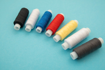 Fototapeta na wymiar Set of sewing threads beautiful color (blue,yellow, green, white, black) on blue background