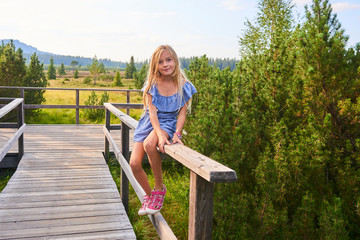 Child blond girl enjoying nature in Jezerni slat (Lake Moor) in National Park Sumava (Bohemian Forest), Czech Republic