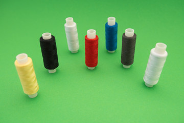 Set of sewing threads beautiful color (blue,yellow, green, white, black) on green background with space for text