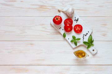 Beautiful fresh raw tomatoes, basil and garlic. Top view, close-up on white wooden background