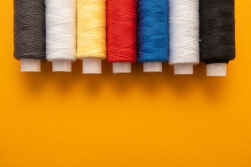 Set of sewing threads beautiful color (blue,yellow, green, white, black) on yellow background with space for text