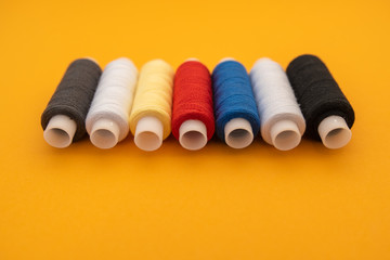 Set of sewing threads beautiful color (blue,yellow, green, white, black) on yellow background with space for text