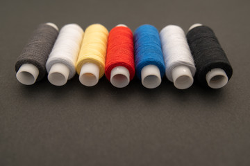 Set of sewing threads beautiful color (blue,yellow, green, white, black) on black background with space for text