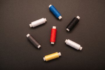 Set of sewing threads beautiful color (blue,yellow, green, white, black) on black background with space for text