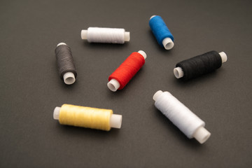 Set of sewing threads beautiful color (blue,yellow, green, white, black) on black background with space for text