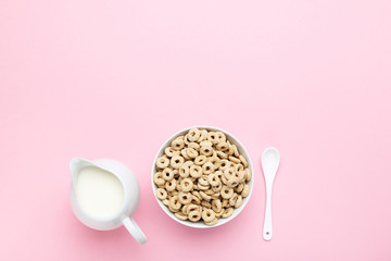 Corn rings with milk in jar and spoon on pink background