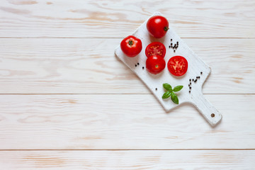 Beautiful fresh raw tomatoes, basil and garlic. Top view, close-up on white wooden background
