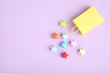 Colorful paper stars with shopping bag on pink background