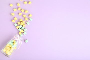 Colorful paper stars in glass jar on pink background